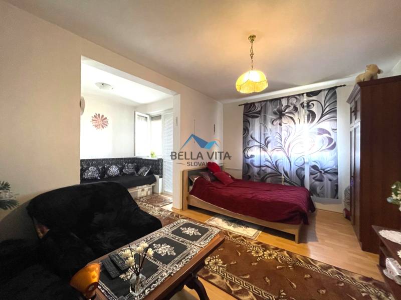 Gemütliche 1-Zimmer-Wohnung mit Holzboden, Bett und Sofa mit Blumenmuster.