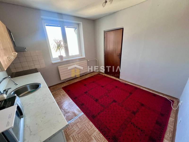 Die Küche einer 3-Zimmer-Wohnung mit Teppichboden, Holzbodenoptik und einfacher Einrichtung.