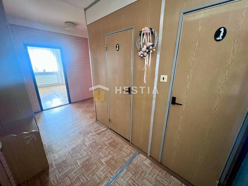 Flur in einer 3-Zimmer-Wohnung mit Holzboden und dekorativem Kranz an der Tür.