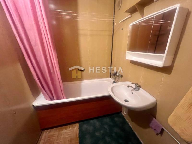 Badezimmer mit Waschbecken und Badewanne in einer 3-Zimmer-Wohnung, der rosa Vorhang fügt ein auffälliges Element hinzu.