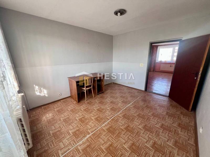 Ein Zimmer in einer 3-Zimmer-Wohnung mit einem Holzboden und einem einfachen Schreibtisch.