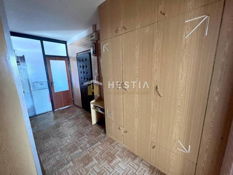 Flur in einer 3-Zimmer-Wohnung mit einem Schrank und einem Boden in Holzoptik.