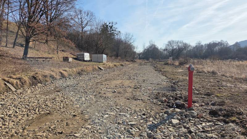 Grundstücke - Wohnen in Haniska, steiniger Weg zwischen Bäumen und Container.