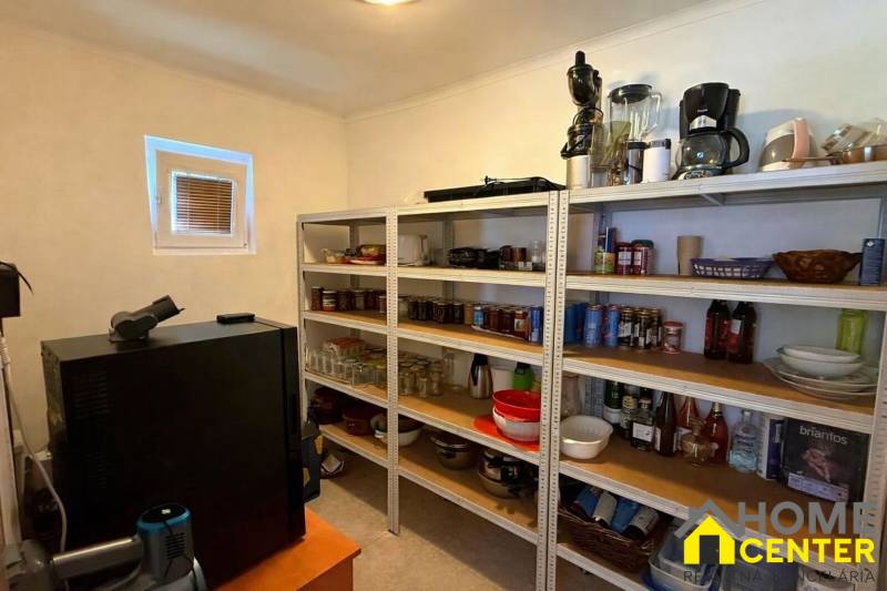 Komora v rodinnom dome s policami plnými zásob a kuchynských spotrebičov.