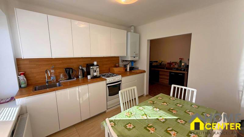 Eine Küche in einem Einfamilienhaus mit weißen Schränken, Holzelementen und einem Esstisch.