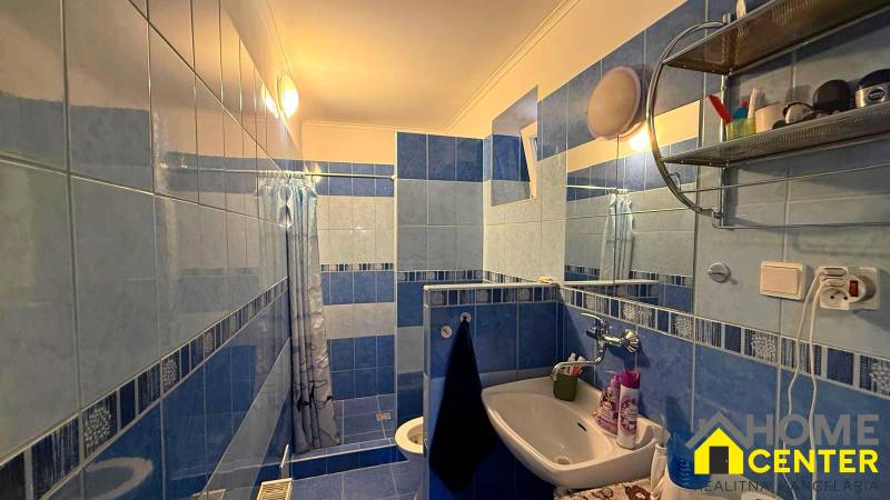 Ein Badezimmer in einem Einfamilienhaus mit blau-weißen Fliesen, einem Waschbecken und einer Duschkabine.