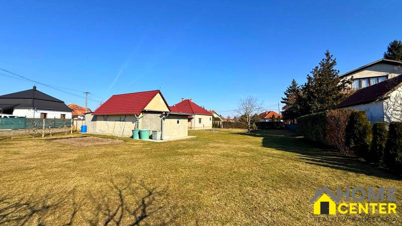 Eine Rasenfläche bei einem Einfamilienhaus in Zemianska Olča mit mehreren Häusern und Sträuchern.