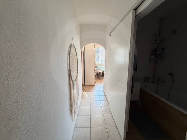 Flur mit Fliesen in einer 3-Zimmer-Wohnung mit Wanddekoration und Blick ins Badezimmer.