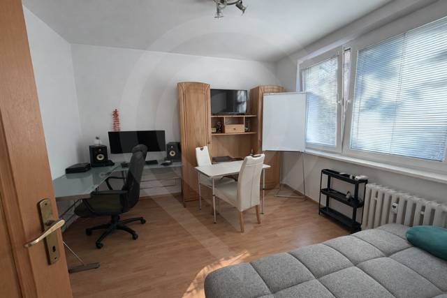 Innenraum einer 3-Zimmer-Wohnung mit Holzboden, Schreibtisch und Sofa.