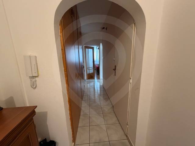 Ein Flur mit hellem Fliesenboden, einem Bogenübergang und einem Schrank in einer 3-Zimmer-Wohnung.