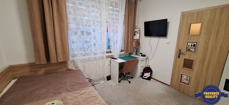Ein Zimmer in einer 4-Zimmer-Wohnung mit einem Tisch, einem Bett und einem Fernseher, Holzboden.