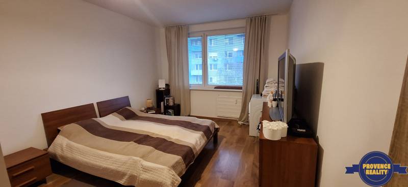 Schlafzimmer in einer 4-Zimmer-Wohnung mit Holzboden und großem Bett.