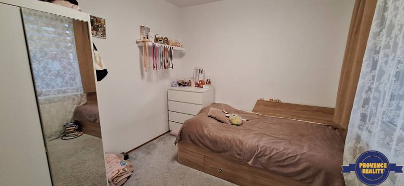 Schlafzimmer in einer 4-Zimmer-Wohnung mit begehbarem Kleiderschrank, Bett und weißer Kommode.