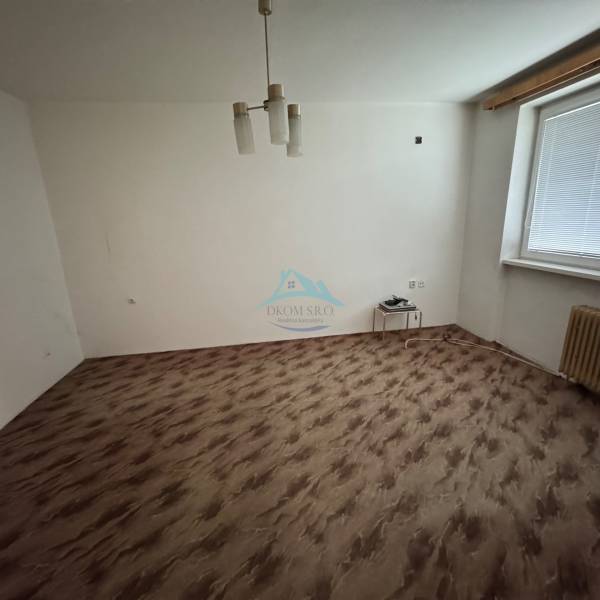 Ein Zimmer in einer Einzimmerwohnung mit einem Boden in Holzoptik und einfacher Beleuchtung.