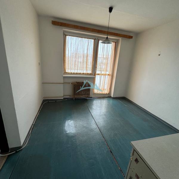 Einfaches Zimmer in einer Einzimmerwohnung mit Fenster und Heizkörper, Boden mit dunklem Dekor.