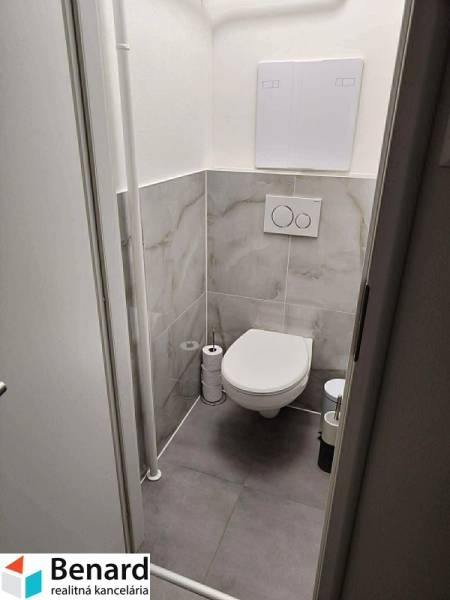 Toilette mit Fliesen und hängendem WC in einer 2-Zimmer-Wohnung.