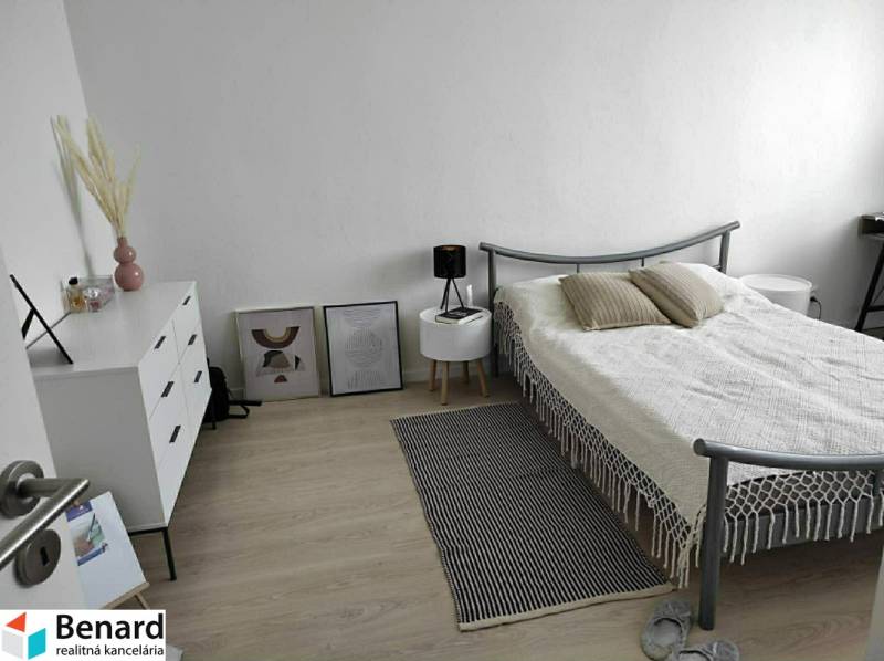 Schlafzimmer in einer 2-Zimmer-Wohnung mit hellen Möbeln und einem Boden in Holzoptik.