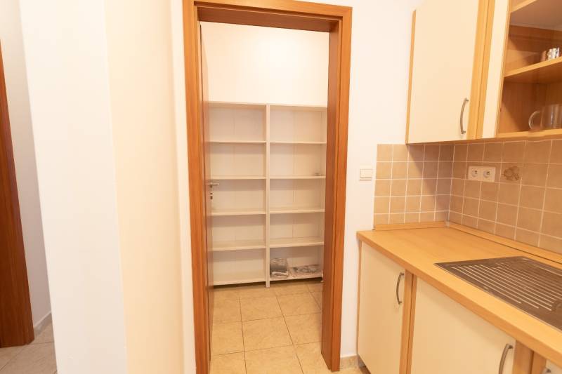 Küche in einer 2-Zimmer-Wohnung mit Regalen und Fliesen, Schränke mit Holzdekor.