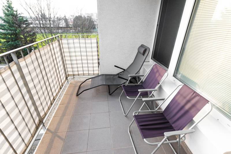 Balkon einer 2-Zimmer-Wohnung mit Metallgeländer und drei Klappstühlen in der Hrachova-Straße, Bratislava - Ružinov.