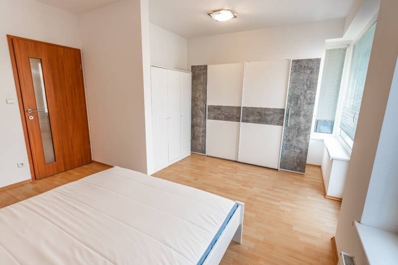 Schlafzimmer mit Bett, Kleiderschrank und Holzboden in einer Zweizimmerwohnung.