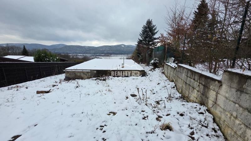 Verschneite Erholungsgrundstücke in Považská Bystrica mit Blick auf die Berge und gepflanzten Bäumen.