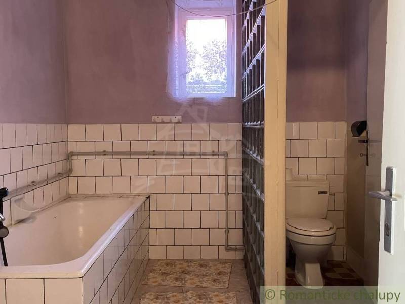 Badezimmer in einem Einfamilienhaus mit Badewanne, Toilette und Fensterglas.