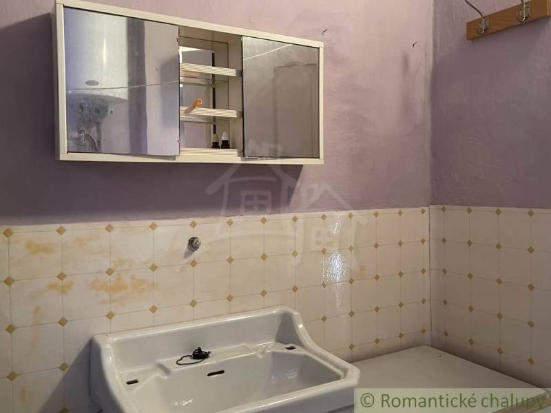 Badezimmer in einem Einfamilienhaus mit Waschbecken und Spiegelschrank an der Wand.