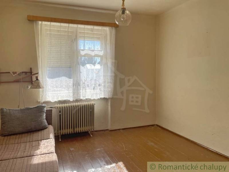 Ein Zimmer in einem Einfamilienhaus mit einem Sofa, einem Fenster und einem Boden mit Holzdekor.