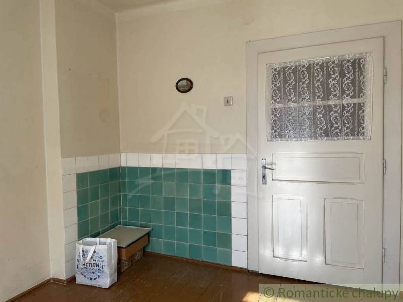 Innenraum eines Einfamilienhauses mit weißen Türen und grün-weißen Fliesen an den Wänden.