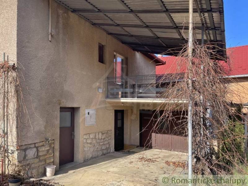 Ein Einfamilienhaus in Bretka mit Balkon, Garage und einem Unterstand für Kletterpflanzen.
