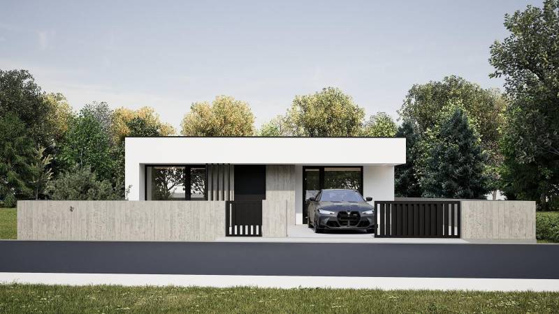 Ein Einfamilienhaus in Nesvady mit einer Betonmauer und einer Garage neben einer grünen Umgebung.