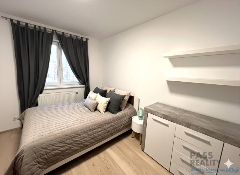 Schlafzimmer in einer 2-Zimmer-Wohnung mit Bett, Kommode und Vorhängen, Boden mit Holzdekor.