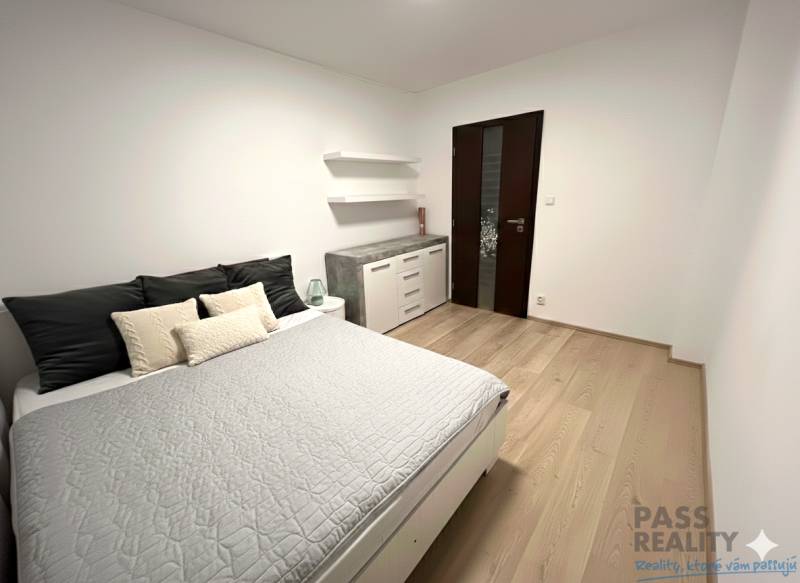 Schlafzimmer mit grauem Bett, Schrank und Boden mit Holzdekor in einer 2-Zimmer-Wohnung.