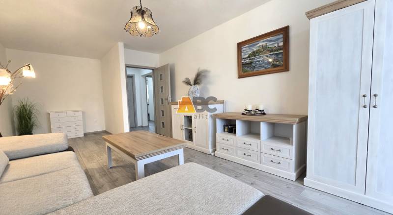 Wohnzimmer in einer Zweizimmerwohnung mit hellen Möbeln und einem Boden in Holzoptik.