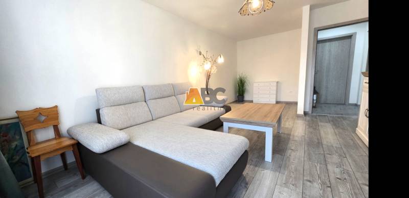 Wohnzimmer mit Sofa und Holzboden in einer Zweizimmerwohnung.