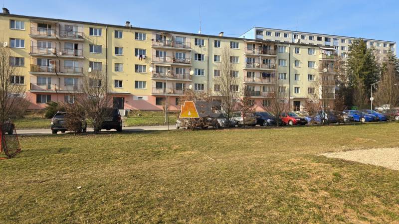 Ein Plattenbau in der Prachatická Straße in Zvolen, vor dem Autos parken.