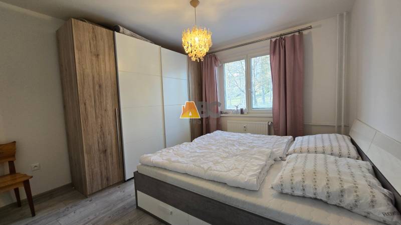 Schlafzimmer in einer 2-Zimmer-Wohnung mit großem Schrank und Bett, Boden mit Holzdekor.