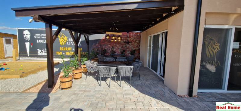 Gastronomiebereiche in Nová Dedinka mit Außensitzplätzen und Ziegelmauer.