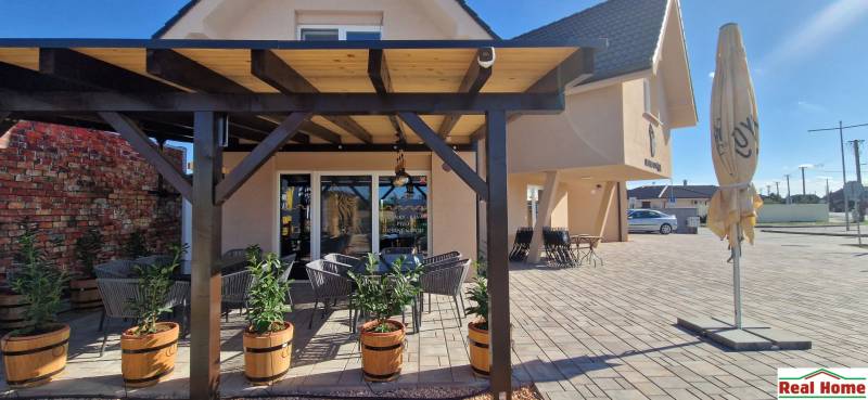 Gastroräume in Nová Dedinka mit Pergola, Blumenkästen und Außensitzbereich auf Pflastersteinen.