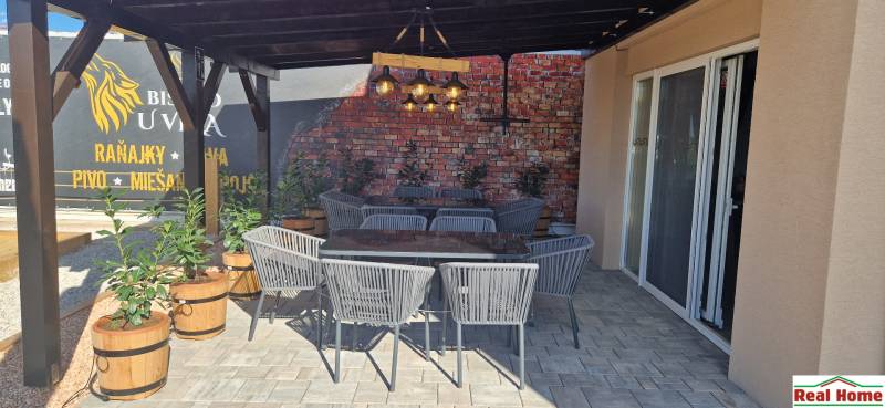 In den Außenbereichen der Gastronomie in Nová Dedinka gibt es Rattan-Stühle und eine Ziegelwand.