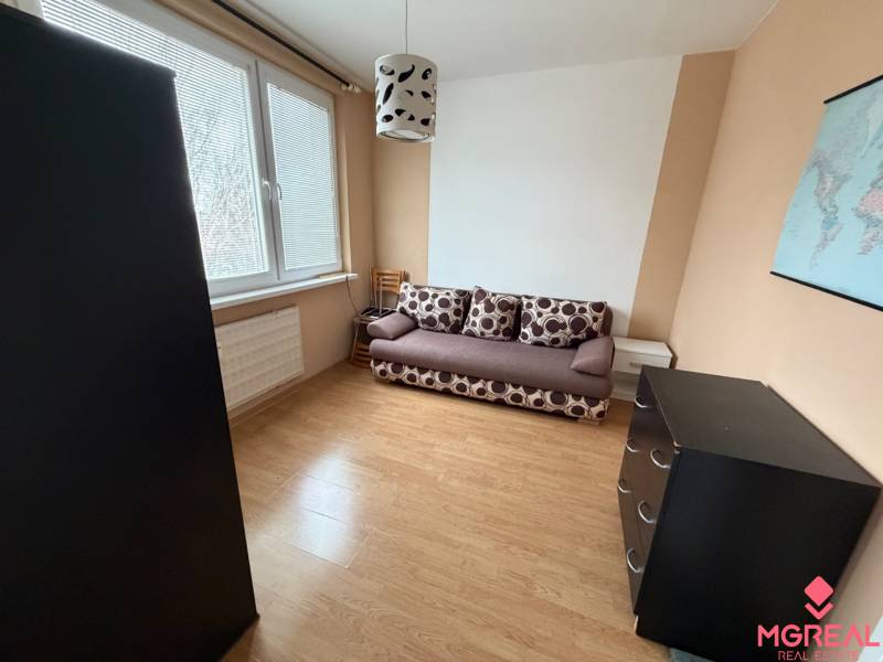 Ein Zimmer mit einem Sofa, einer Kommode und einem Boden in Holzoptik in einer 3-Zimmer-Wohnung.