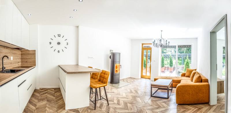 Helle Ferienwohnung mit Küche, orangefarbenem Sofa und Holzdekorboden.