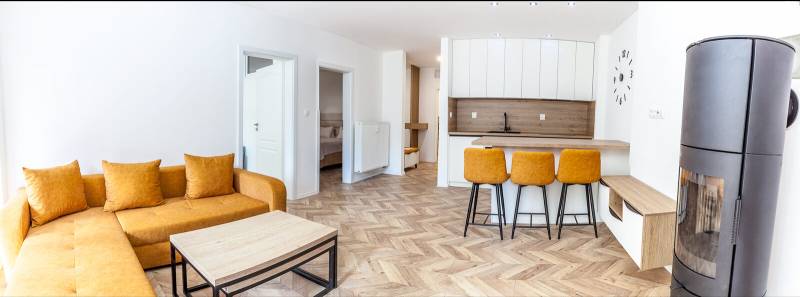 Ferienwohnung mit Sofa, Küchentheke und Holzboden.