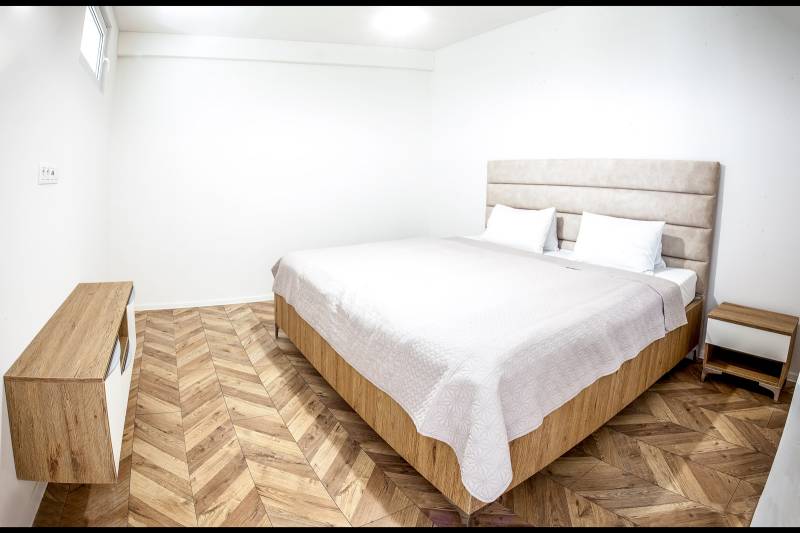 Schlafzimmer in einer Ferienwohnung mit Bett und Boden in Holzoptik.