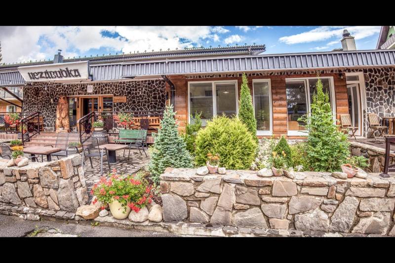Steinfassade des Ferienapartments in Štrba mit Terrasse und Blumenschmuck.