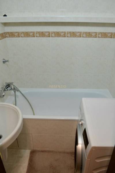 Badezimmer mit Badewanne, Waschmaschine und weißen Fliesen in einer 2-Zimmer-Wohnung.