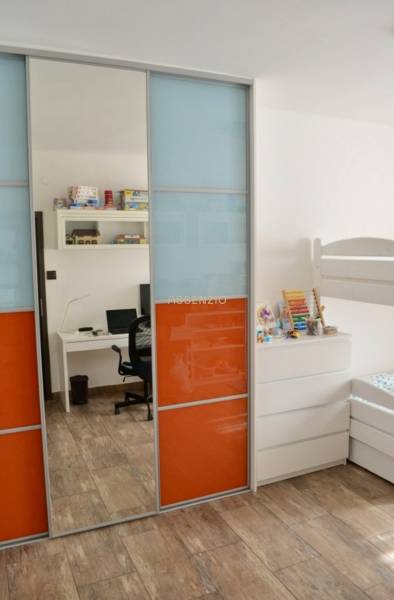 Kinderzimmer mit Etagenbett, buntem Schrank und Boden in Holzoptik.