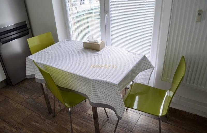 Esszimmer mit offenem Fenster, zwei Stühlen und Holzboden in einer Zweizimmerwohnung.