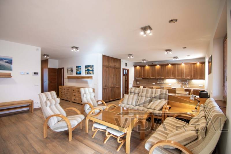 Innenraum eines Einfamilienhauses mit geräumigem Wohnzimmer, Küchenzeile und Boden mit Holzdekor.