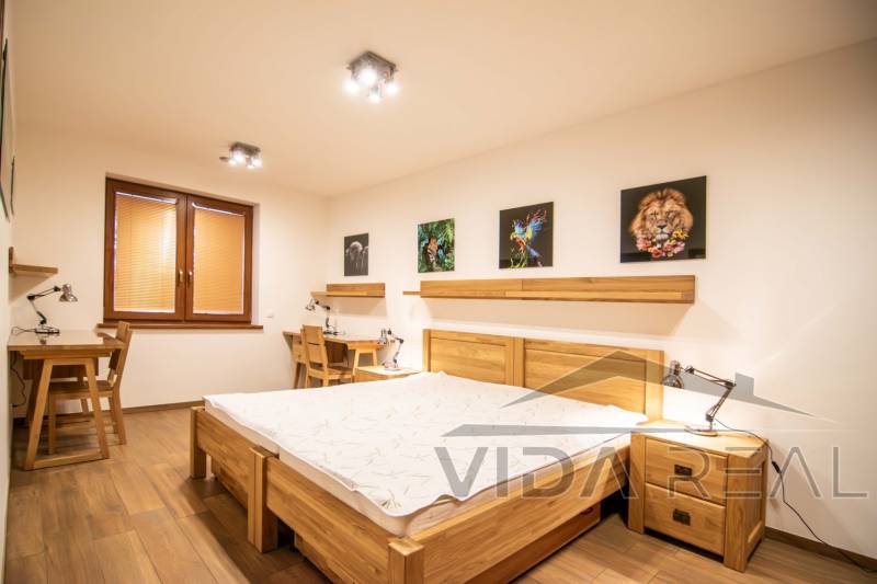 Schlafzimmer in einem Einfamilienhaus mit Holzboden, Bildern und Arbeitstischen.